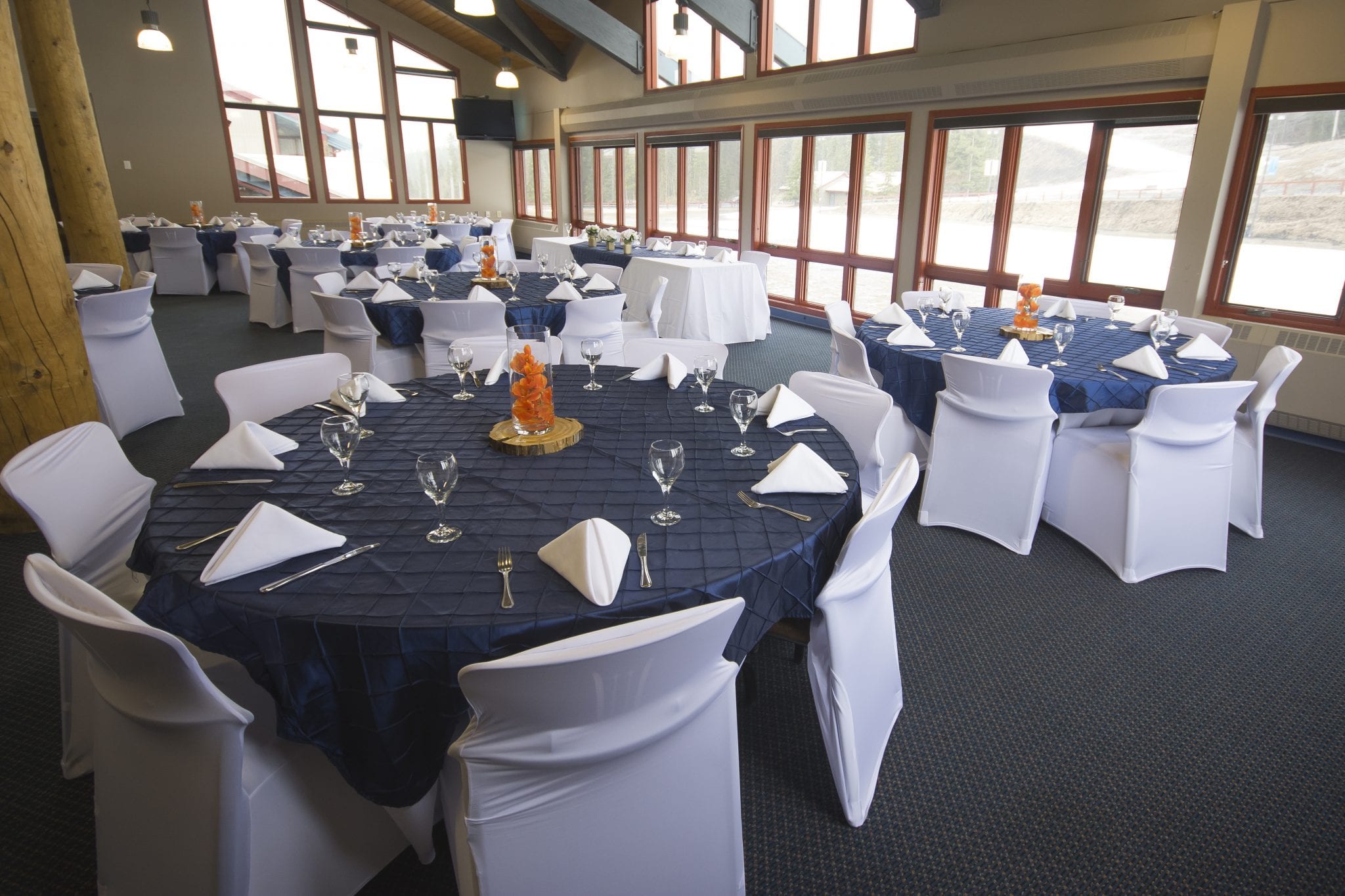 Wedding reception set up with navy overlays, white napkins at the Canmore Nordic Centre